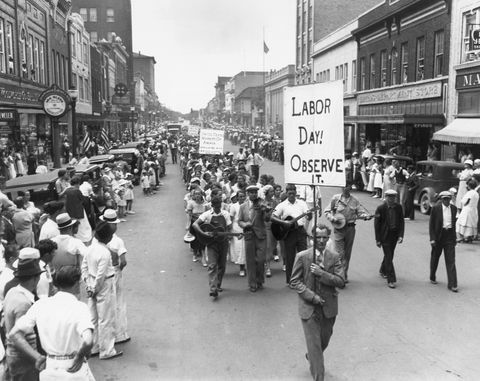 parada w święto pracy w 1934 r., w której ludzie chodzą po ulicy trzymając znaki, a tłum obserwuje z chodników