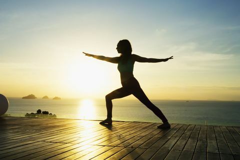 Kobieta robi joga nad morzem o zachodzie słońca