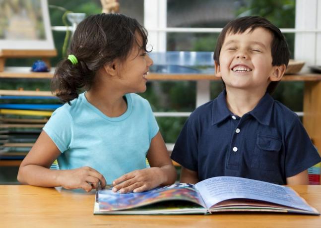 dwójka roześmianych dzieci czytających książkę w szkole