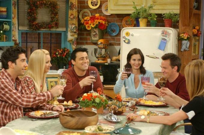 Ross, Phoebe, Joey, Monica, Chandler i Rachel z programu telewizyjnego przyjaciele zebrali się wokół stołu wznosząc toast kieliszkami