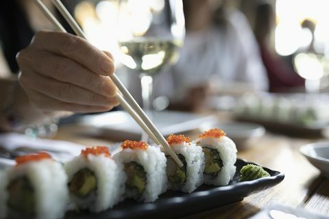 Kobieta z pałeczkami sięgania sushi na tacy restauracji