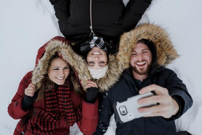 Przyjaciele z dużym kątem robiący selfie leżąc na pokrytym śniegiem polu