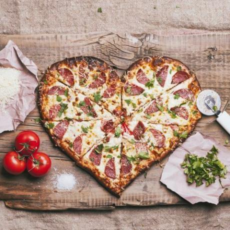 pizza w kształcie serca i składniki na desce do krojenia