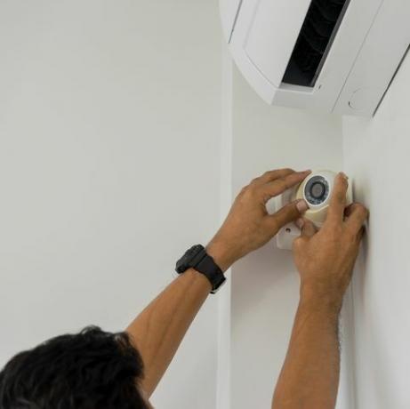 przycięty mężczyzna ręcznie instalujący cctv na ścianie w domu