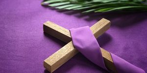 religijny krzyż i liście palmowe na fioletowym tle