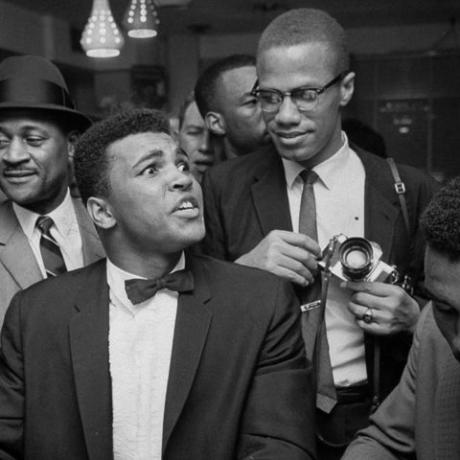 miami marzec 1964 czarny przywódca muzułmański Malcolm x 2r, drażniąco oparty na ramieniu odzianego w smoking Cassius Clay, teraz Muhammad Ali l, który siedzi zadowolony z siebie przy ladzie z fontanną sodową, otoczony radosnymi fanami po tym, jak pokonał Sonny'ego Listona na mistrzostwa świata w wadze ciężkiej zdjęcie autorstwa boba gomelta kolekcja zdjęć życia za pośrednictwem getty imagesgetty images