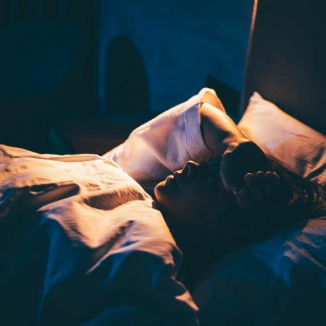 kobieta cierpiąca na bezsenność młoda kobieta leży na łóżku z ręką na czole