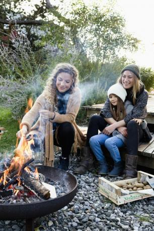 dwie kobiety i dziewczyna siedzą przy ognisku, odpoczywają