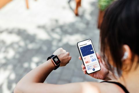 młoda kobieta korzystająca z aplikacji fitness tracker na inteligentnym zegarku i smartfonie