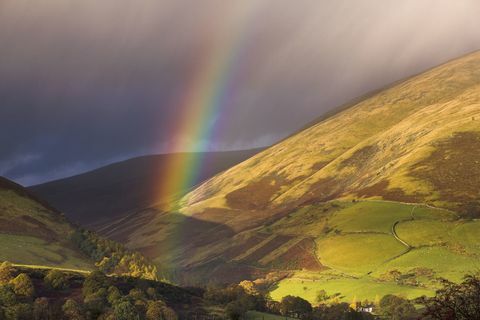 Rainbow i burzowe chmury na wzgórzach wsi