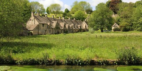 Widok na Bibury, Gloucestershire z łąką wodną na pierwszym planie i za domkami falców Cotswold